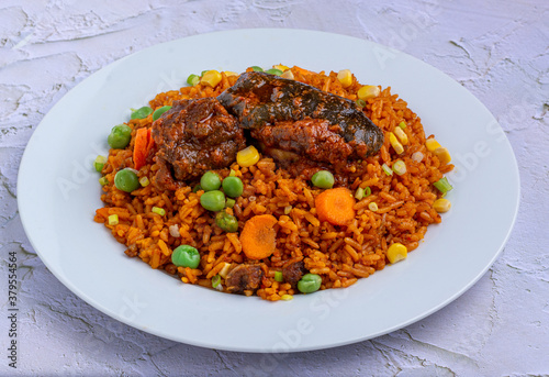 Jollof Rice with stewed goat meat served on a white plate
