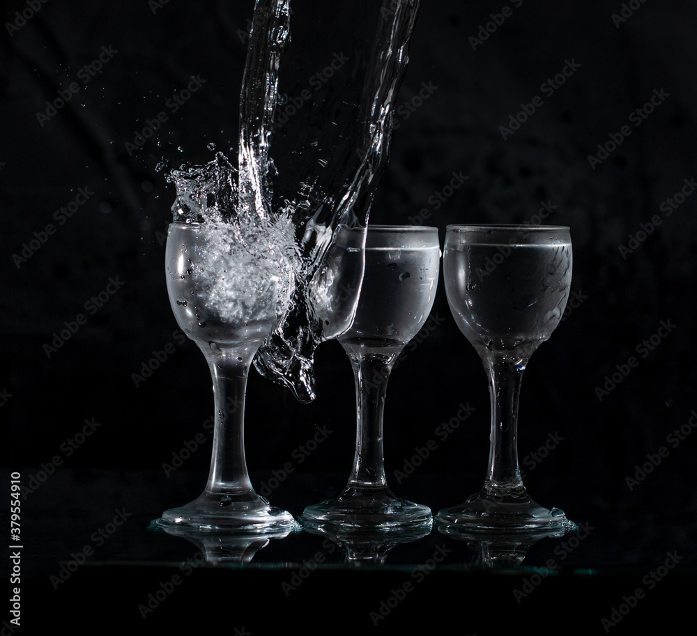 glasses with water with splashes on a black background glasses with water with splashes on a black background