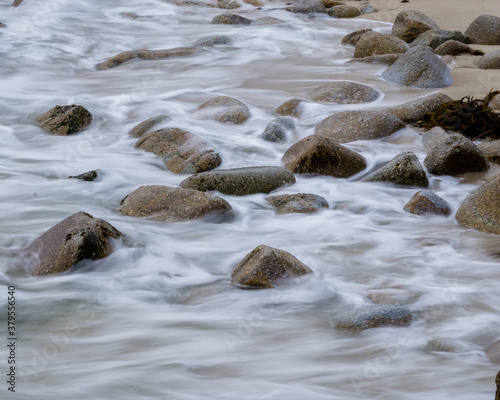 Long exposure Pacific seascape waves on the rocky stoney shore. Slow shutter speed used to see the movement (Soft focus shot)