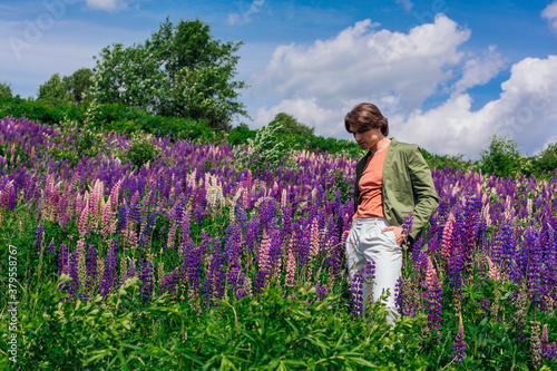 Tall handsome man standing on lupine flowers field