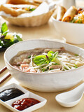 vietnamamese meal with beef pho bo soup accompanied by hoisin sauce and sriracha