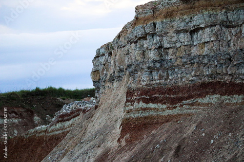 textures of various clay layers underground in clay quarry after geological study of soil. colored layers of clay and stone in section of earth, different rock formations and soil layers.