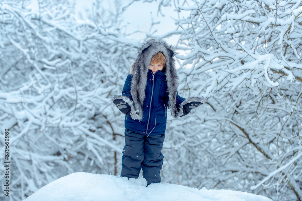 Cute toddler boy playing in winter park in snow outdoors. Kids in winter clothes. Childhood memories - beautiful snowy winter over meadow. Cute toddler boy playing in winter park in snow outdoors. Kids in winter clothes. Childhood memories - beautiful snowy winter over meadow.