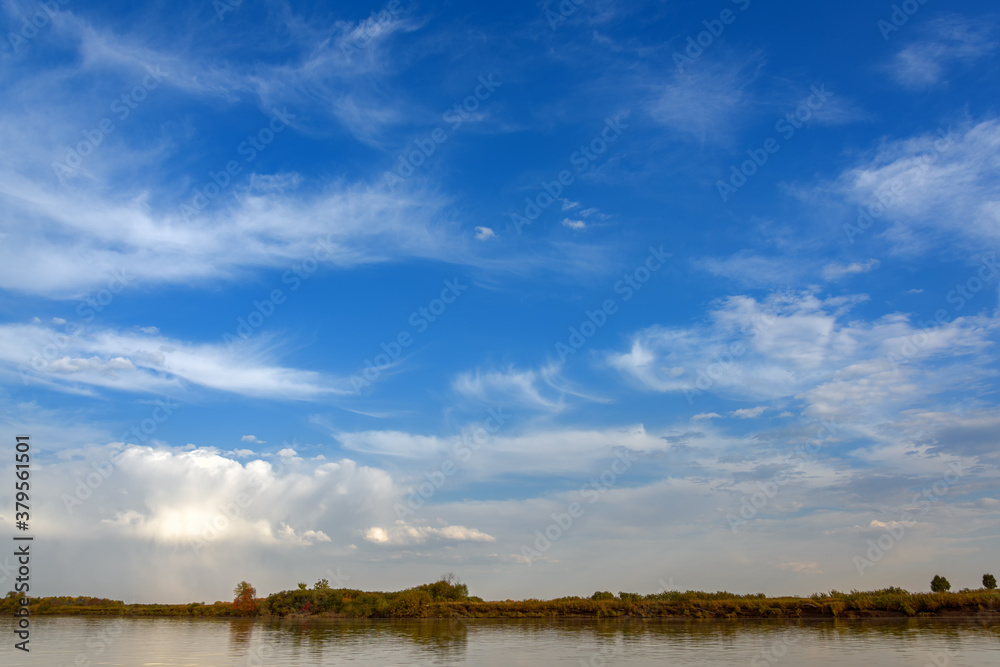 Obraz premium landscape on the river, blue sky with clouds, Bank edge with autumn forest