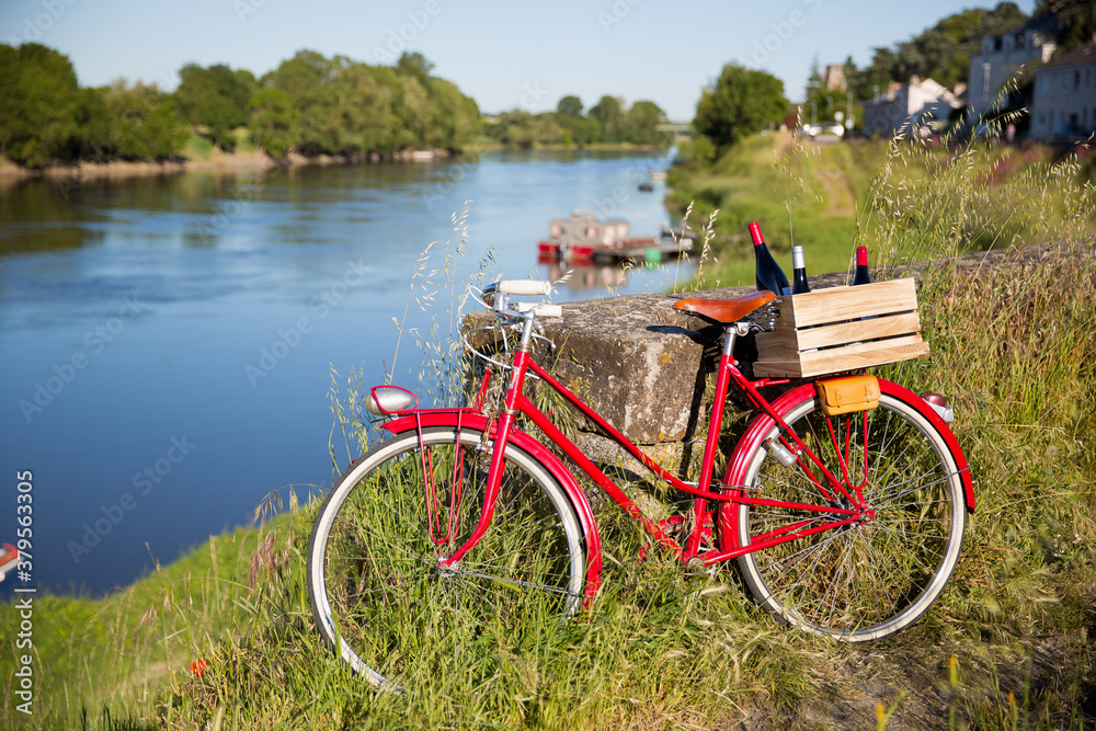 Vieux vélo rouge en bord de la Loire abandonné par un vigneron, caisse de vin dans une caisse en bois.