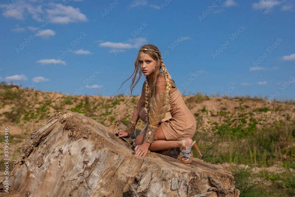 Naklejka premium teen girl in stylish fantasy clothes in vintage middle eastern style ornate with gold jewelry in the setting sun