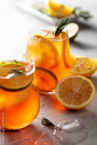 Traditional iced tea with lemon, lime and ice garnished with rosemary twigs.