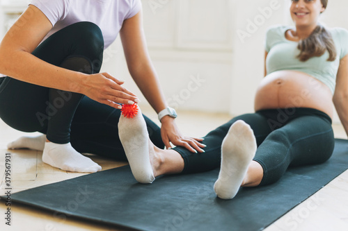 The trainer massages female feet with spiked ball, prevention of flat feet