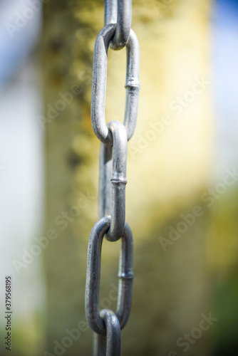 metal chain. Links of aluminum chain on the background of a green pipe