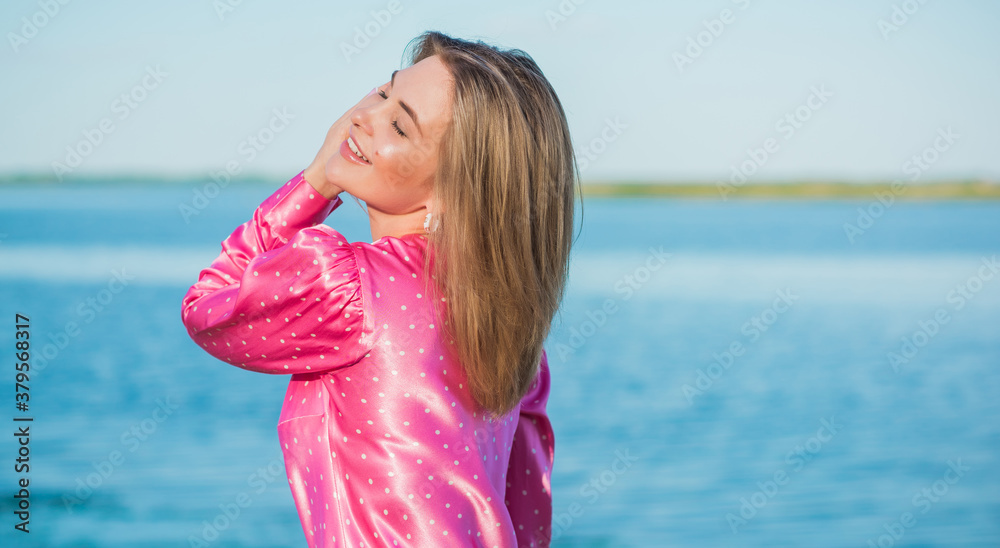 Fashionable happy woman in pink silk polka dot dress. Modern blonde hair woman at nurture in fancy romantic style Fashionable happy woman in pink silk polka dot dress. Modern blonde hair woman at nurture in fancy romantic style