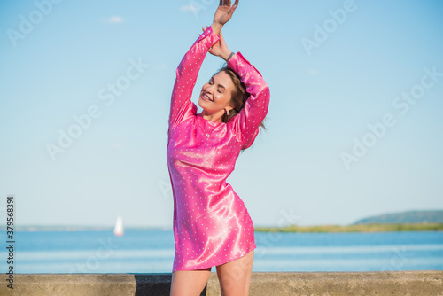 Fashionable happy woman in pink silk polka dot dress. Modern blonde hair woman at nurture in fancy romantic style 