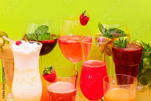 Summer drinks with fruit juice and ice. Refreshing summer beverages in different glasses over green background.