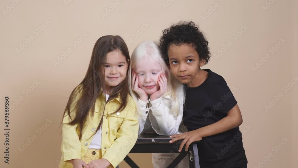 Three diverse children with unusual appearance hug each other, posing. Three diverse children with unusual appearance hug each other, posing.