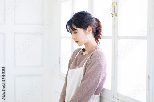 部屋の窓際に立つ若い女性