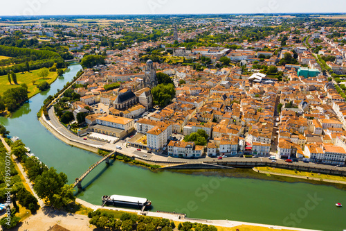 Aerial view of French town of Saintes on banks of Charente river overlooking medieval Roman Catholic cathedral on summer day..