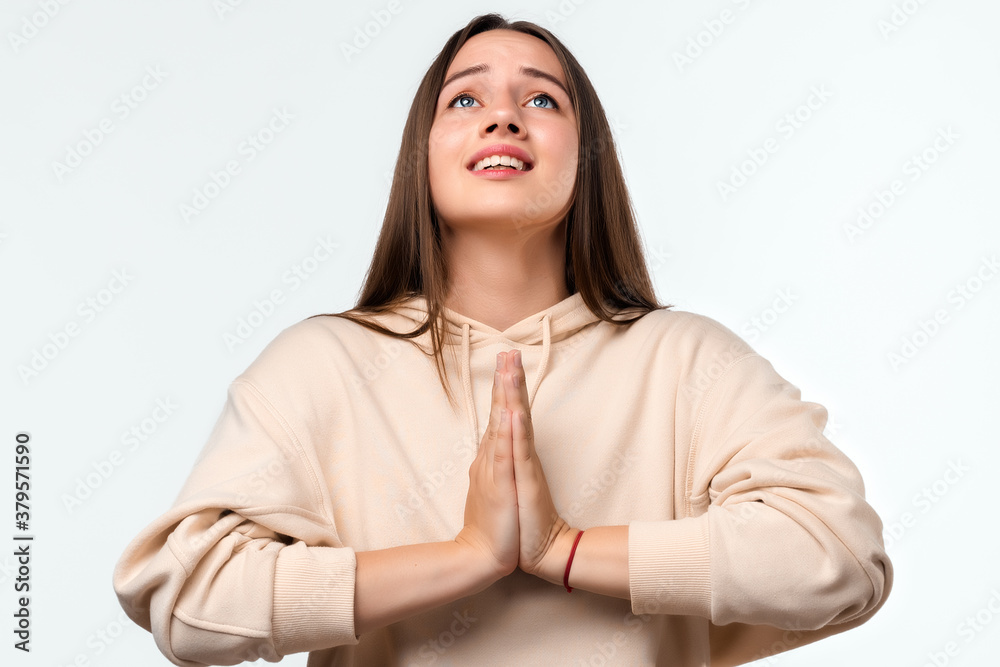 Image of pleased brunette woman with long hair smiling and holding palms together Image of pleased brunette woman with long hair smiling and holding palms together