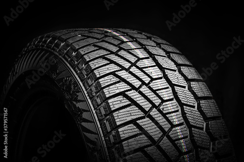 winter tire, friction for snow and ice. asymmetrical tread pattern. close-up on a black background