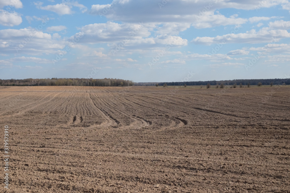 Fototapeta premium A plowed agricultural field. Blue sky over a farm field.