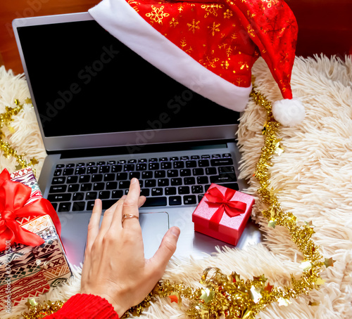 Christmas online shopping top view. Female buyer makes order on laptop, copy space on screen. © Elena