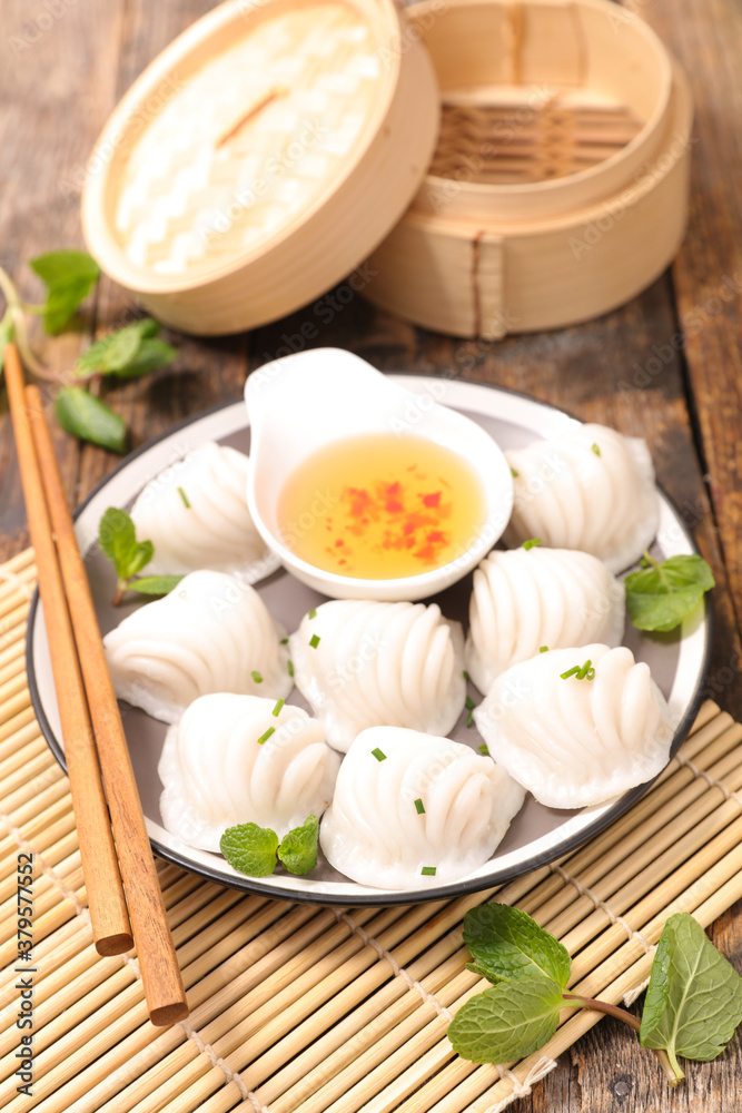 traditional chinese steamed dumplings dim sums in bamboo steamer and chopsticks