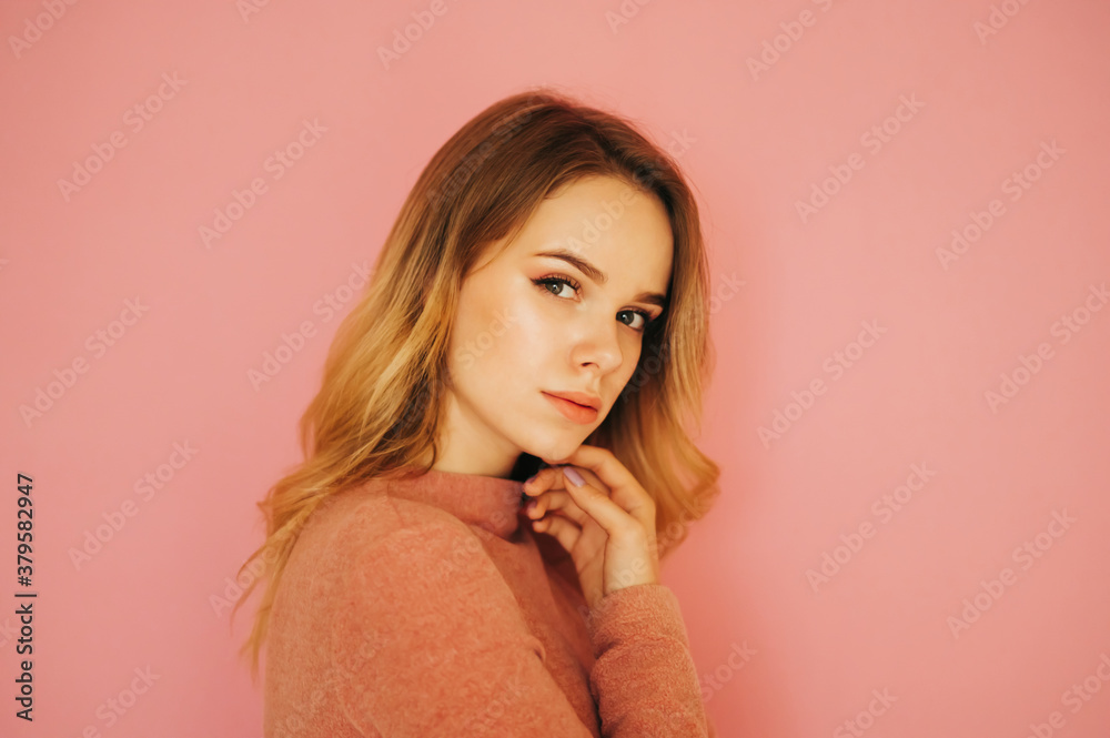 Close portrait of a cute woman in a sweater, isolated on a pink background, looking and posing at the camera with a serious face. Close portrait of a cute woman in a sweater, isolated on a pink background, looking and posing at the camera with a serious face.