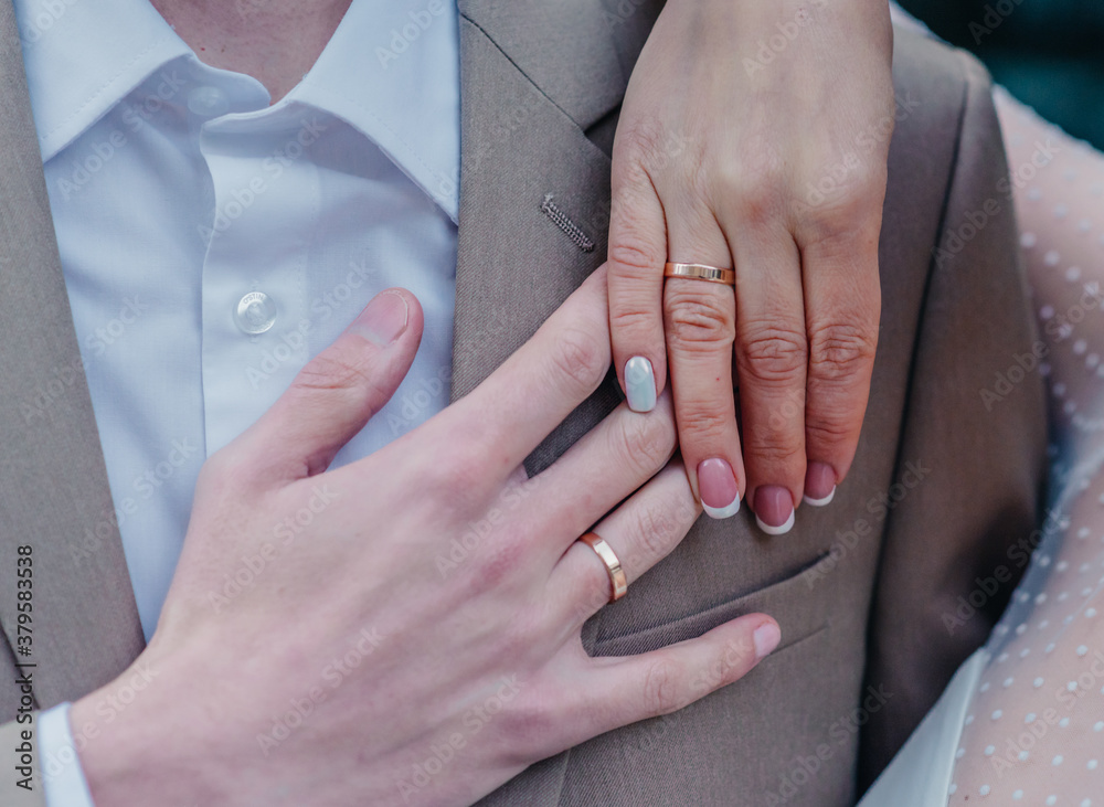 bride's hand with an elegant wedding ring with white gold diamonds on a bouquet of their peonies bride's hand with an elegant wedding ring with white gold diamonds on a bouquet of their peonies