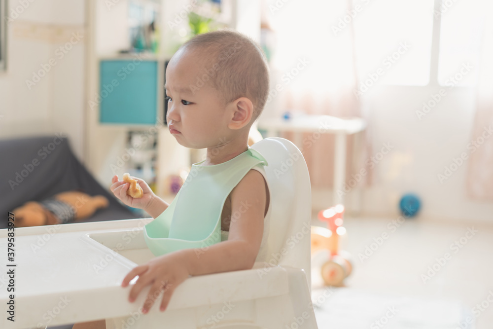 A one-and-a-half-year-old boy eats in a dining chair A one-and-a-half-year-old boy eats in a dining chair