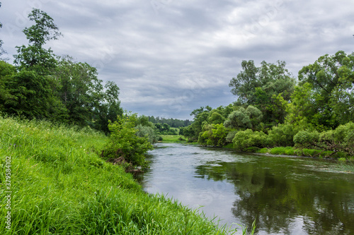 River perspective. Trees and bushes on the banks. Gloomy sky. The Protva River in Russia in the middle of summer  a great place for tourism.