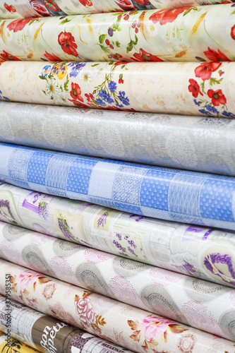 Background with many different tablecloths of oilcloth tablecloths in rolls a presentation to choose from in a store hanging on a showcase for sale