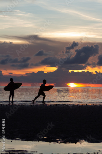 Niños haciendo surf en la playa con atardecer de fondo © BarefootHumans