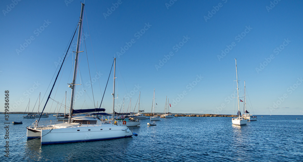 Panoramic of a catamaran anchored on a beach in the Formentera island during sunset. Calm ocean water in the coast in the mediterranean sea.