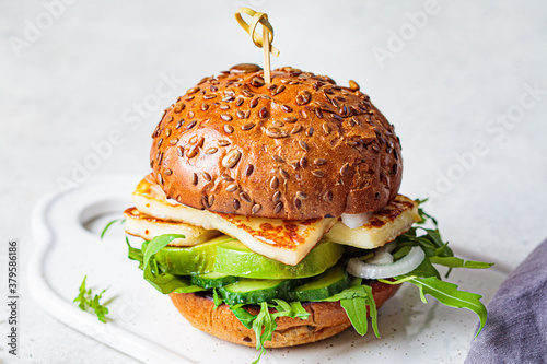 Grilled halloumi burger with slices of avocado and arugula. Vegetarian food concept. photo