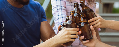 Team. Hands of friends, colleagues during beer drinking, having fun, clinking bottles, glasses together. Flyer with copyspace. Oktoberfest, friendship, togetherness, happiness holidays concept