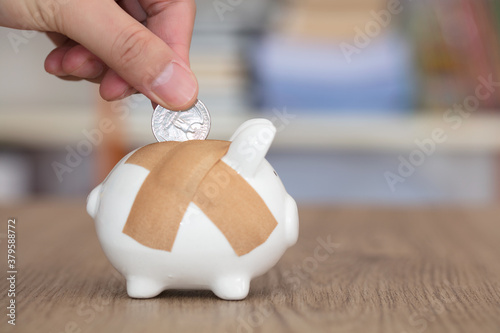 Put the coin into the piggy bank with band-aid