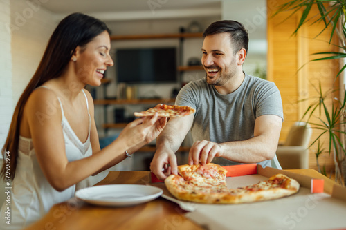 Smiling couple enjoying pizza for breakfast, portrait.