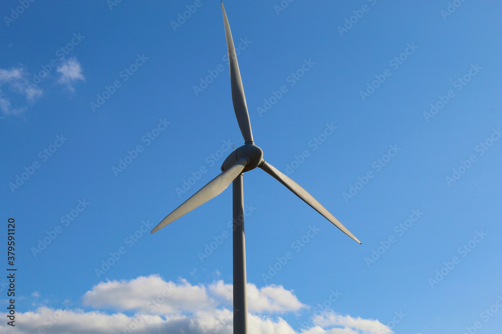 wind generator spinning against a blue sky, clean energy
