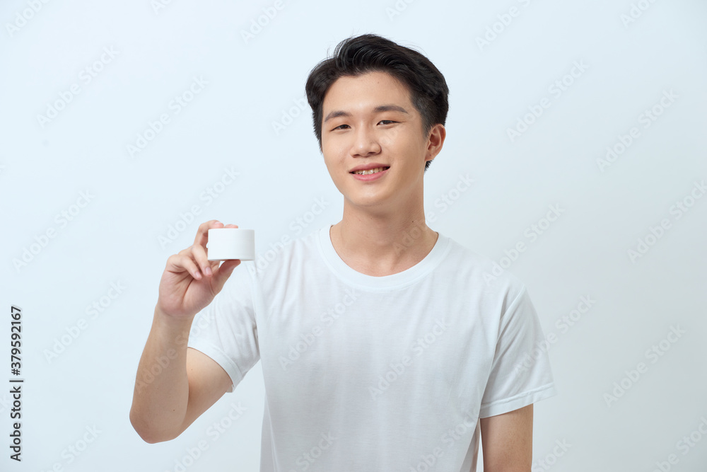 Amazing man advising recommendation buy, holding facial cream isolated grey background Amazing man advising recommendation buy, holding facial cream isolated grey background