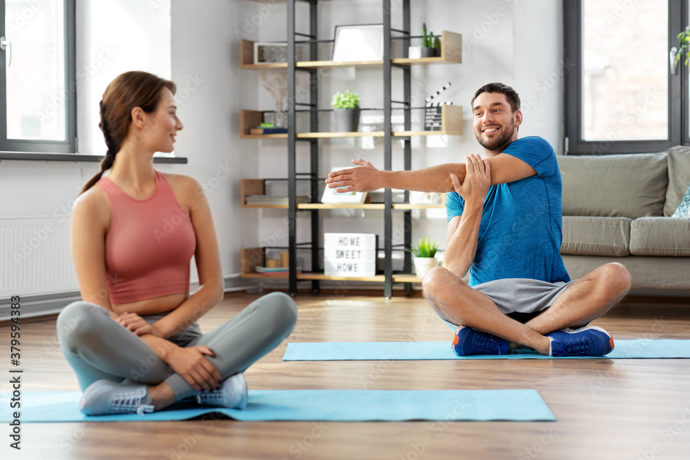 sport, fitness, lifestyle and people concept - smiling man and woman stretching at home