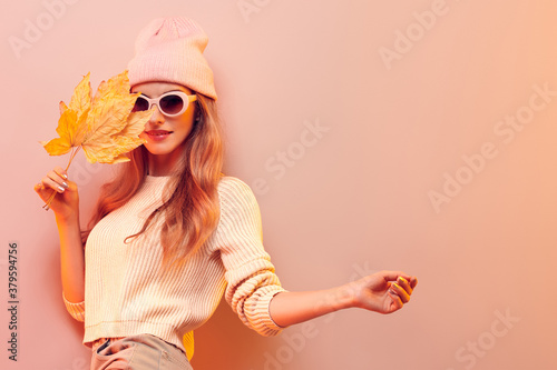Hipster woman in Trendy autumn fall Fashionable outfit, stylish hair, makeup. Blonde in jumper, fashion jeans having fun smiling. Beautiful girl in autumnal beanie hat with maple leaf