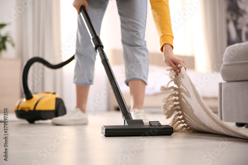 Young woman using vacuum cleaner at home, closeup photo