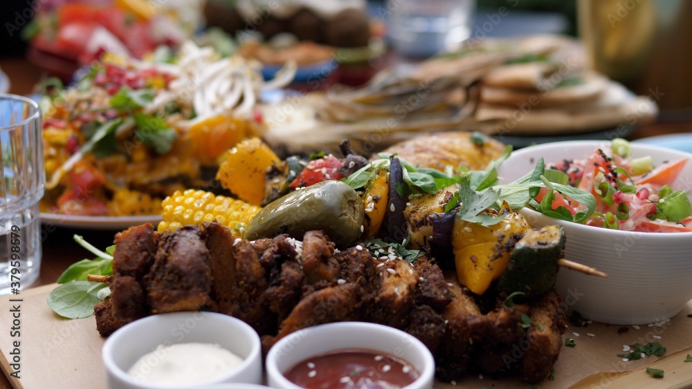 Close up of soy meat and vegetable barbecue served with sauces and a side salad