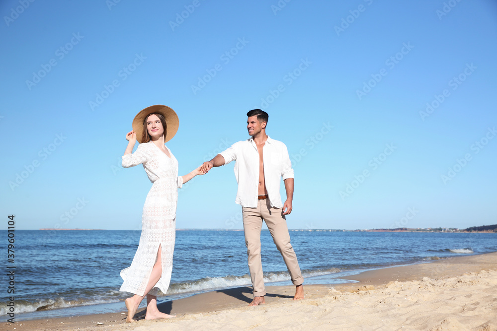 Lovely couple walking together on sandy beach Lovely couple walking together on sandy beach