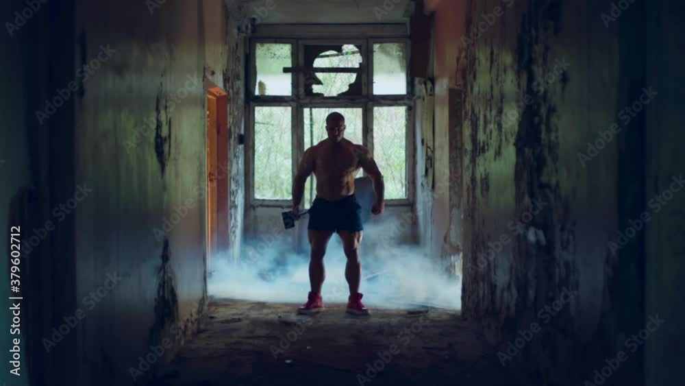 Athletic man doing an exercise with chains in a destroyed building has a naked torso and a bald head Athletic man doing an exercise with chains in a destroyed building has a naked torso and a bald head