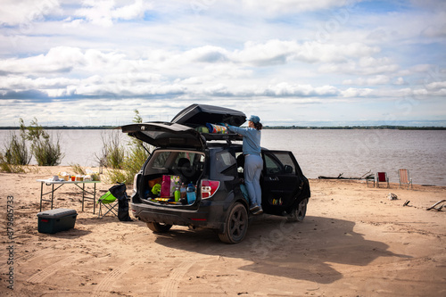 Woman taking off tourist equipment from roof box