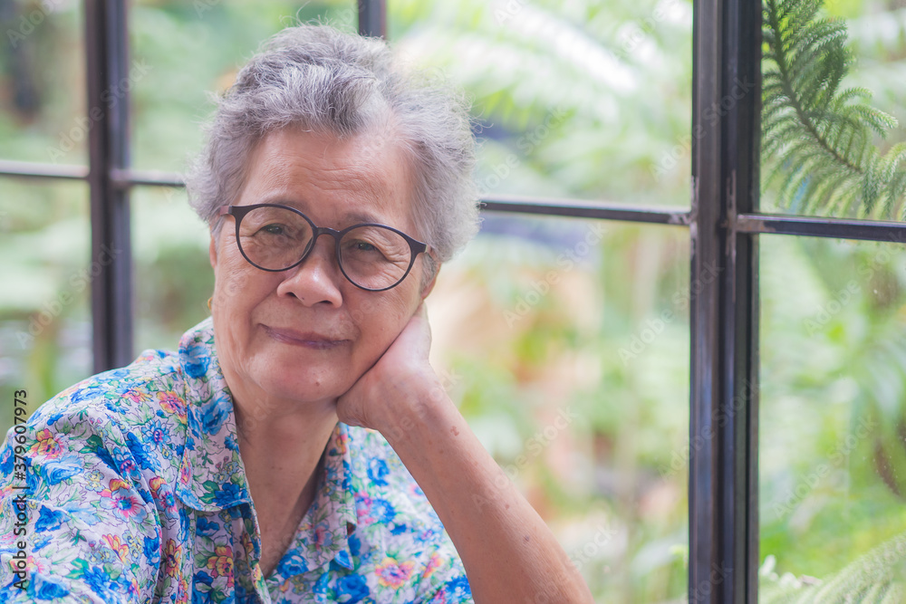 Senior Asian woman smiling and looking at camera while sitting on a chair in the cafe shop Senior Asian woman smiling and looking at camera while sitting on a chair in the cafe shop