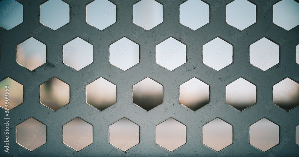 Naklejka premium Abstract drilled hexagon pattern on metal plate with bokeh background
