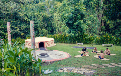 Group of people preparing for Mayan Temazcal- traditional steam sauna bath of Mesoamerican cultures. Diverse multiethnic friends sitting on grass and taking training course before Temazcal experience photo