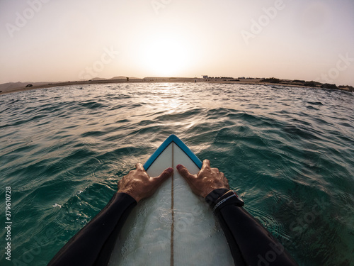 Surfer pov watching sunset in the water sitting on his surf board - Freedom, holidays, vacation concept