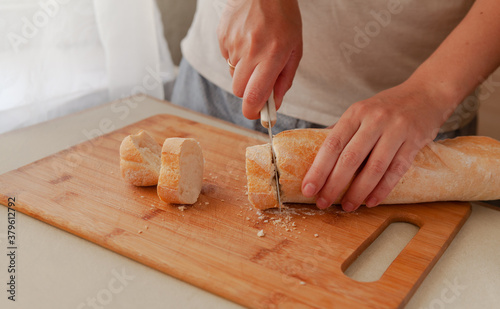 Cutting fresh crispy bread close-up. The woman is cutting bread.