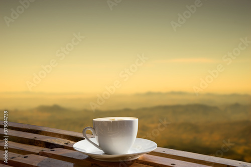 Morning cup of coffee with mountain background at sunrise.